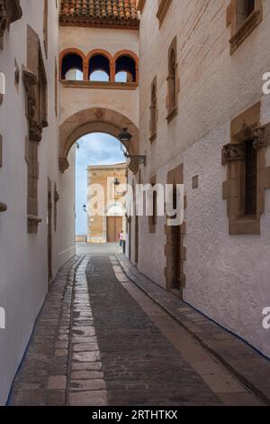 Altstadt von Sitges in Katalonien, Spanien, engen Straße mit gedeckte Bogenbrücke zwischen zwei Gebäuden Stockfoto