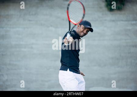 Junger Tennisspieler spielt auf einem Hartplatz und schlägt während eines Spiels einen Ball Stockfoto