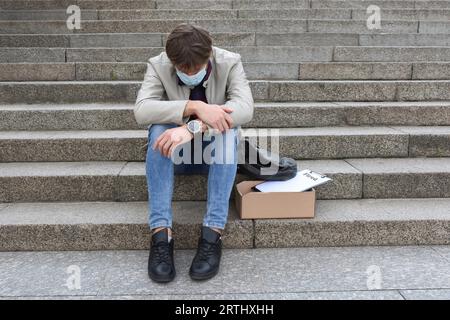 Das Konzept der Arbeitslosigkeit und Entlassungen. Feuerte einen Angestellten, der auf der Treppe saß und an einer schweren Depression litt Stockfoto