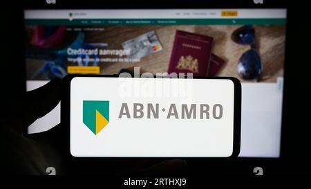 Person, die ein Smartphone mit dem Logo des niederländischen Finanzunternehmens ABN AMRO Bank N.V. auf dem Bildschirm vor der Website hält. Konzentrieren Sie sich auf das Display des Telefons. Stockfoto