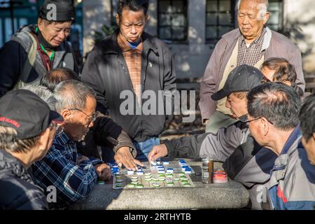 New York, United States of America, 17. November 2016: Eine Gruppe chinesischer Männer spielt ein Brettspiel im Columbus Park in Chinatown Stockfoto
