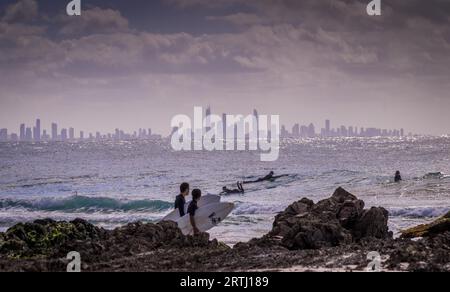 Surfers Paradise, Australien am 16. August 2016: Surfer genießen die Wellen am Snapper rocks mit der Skyline von Surfers Paradise im Hintergrund Stockfoto