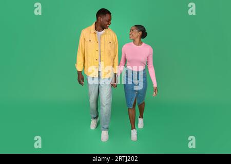Liebes junges afroamerikanisches Paar, das über grünen Hintergrund geht Stockfoto
