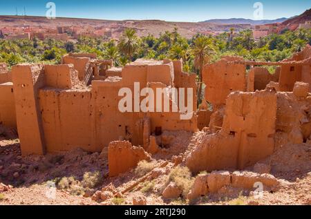 Verlassene antike Kasbah-Ruinen inmitten einer Palmenoase in Tinghir Marokko. Die Ruinen des Lehmziegelhauses stehen entlang einer grünen Oase Stockfoto