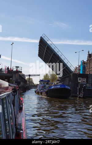 Schiff, das im Frühjahr unter einer offenen Zugbrücke in Amsterdam, Niederlande, vorbeifährt Stockfoto