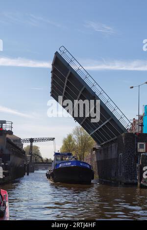 Schiff, das im Frühjahr unter einer offenen Zugbrücke in Amsterdam, Niederlande, vorbeifährt Stockfoto