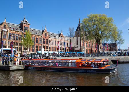 Im Frühjahr legen Sie vor dem Hauptbahnhof in Amsterdam, Niederlande, an. Bootsanlegestelle vor dem Hauptbahnhof in der Innenstadt Stockfoto