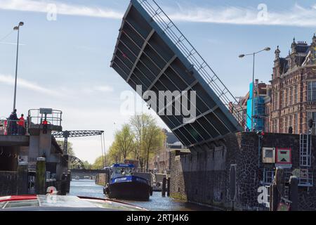 Schiff, das im Frühjahr unter einer offenen Zugbrücke in Amsterdam, Niederlande, vorbeifährt Stockfoto