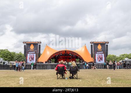 Roskilde, Dänemark, 1. Juli 2016: Zwei Personen sitzen auf dem Roskilde Festival 2016 vor der orangefarbenen Bühne Stockfoto