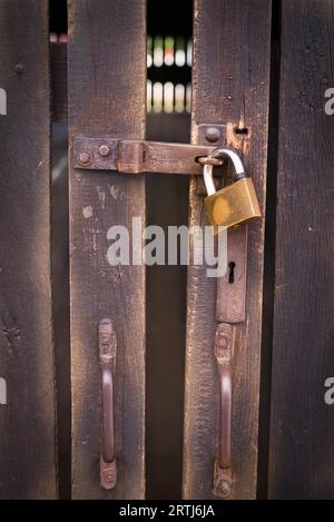 Nahaufnahme eines Vorhängeschlosses mit einem alten Metall Hasp und Grundnahrungsmittel auf einer alten Holztür Stockfoto