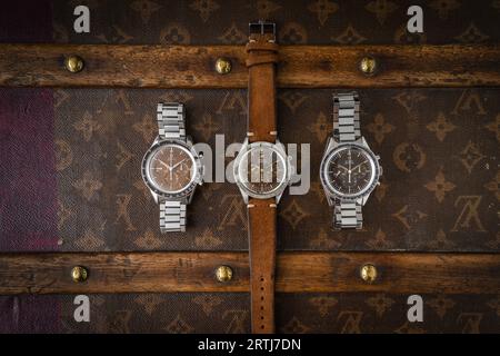 Das klassische Omega Speedmaster Shooting auf einer alten, genieteten Louis Vuitton Reisetasche mit dem kultigen LV-Muster. Stockfoto