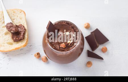 Vegane Schokoladenpaste mit Bananen und Nüssen, umgeben von Zutaten: Schokolade und Haselnüsse auf hellgrauem Hintergrund, Draufsicht Stockfoto