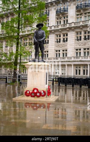 LONDON - 24. April 2023: Die Gurkha-Soldatenstatue steht zwischen roten Mohnkränzen außerhalb des Verteidigungsministeriums, mit reflektierendem nassem Boden Stockfoto