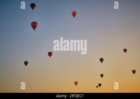 Fliegen Sie Heißluftballons gegen den hellblauen und gelben Morgenhimmel Stockfoto