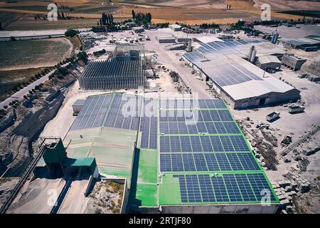 Luftaufnahme von Industriegebäuden mit auf dem Dach installierten Photovoltaikpaneelen. Sonnenkollektoren auf dem Dach eines Industriebaus. Solar-PV-Panels, Luftaufnahme Stockfoto