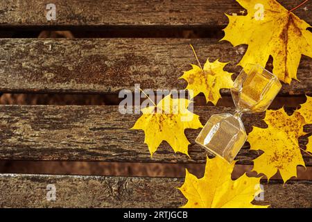 Sanduhr mit umgestürzten Blättern auf Holzbank, Draufsicht Stockfoto