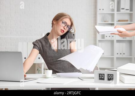 Junge Geschäftsfrau, die mit Dokumenten arbeitet, die noch nicht fristgerecht im Amt sind Stockfoto