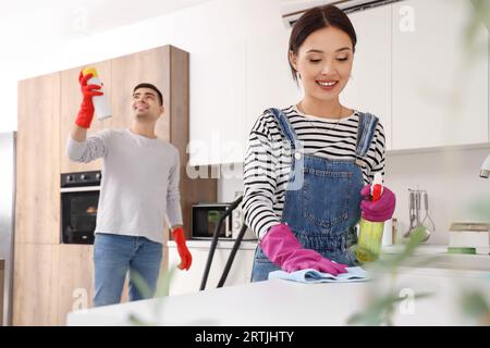 Glückliches junges Paar, das in der Küche putzt Stockfoto