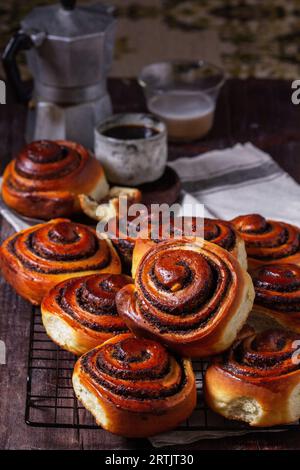 Hefeteig mit Zimt mit Mohnsamen, Rosinen und kandierten Früchten, serviert mit Kaffee. Rustikaler Stil. Stockfoto