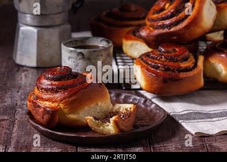 Hefeteig mit Zimt mit Mohnsamen, Rosinen und kandierten Früchten, serviert mit Kaffee. Rustikaler Stil. Stockfoto