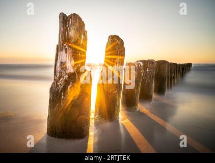 Wunderschöner Sonnenuntergang über dem Meer. Sonnenstrahlen und Wellenbrecher. Stockfoto