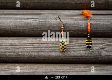 Zwei rote Angelköder hängen an einer grauen Holzwand Stockfoto