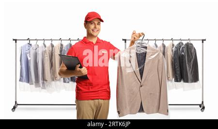 Reinigungspersonal, das einen Anzug und eine Ablage vor Kleiderstangen hält, die auf weißem Hintergrund isoliert sind Stockfoto