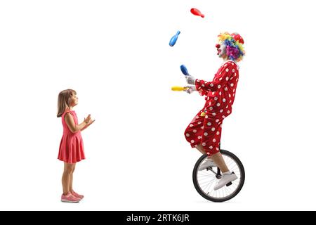 Kleines Mädchen klatscht und beobachtet einen Clowns, der auf einem Einrad reitet und isoliert auf weißem Hintergrund jongliert Stockfoto