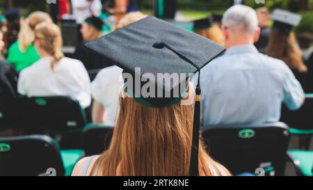 Abschlussfeier in der Universität, weibliche Studenten mit schwarzen Mänteln und akademischer Mortarboard-Kappe, Gruppenklasse von High School-Absolventen erhalten di Stockfoto