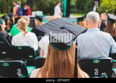 Abschlussfeier in der Universität, weibliche Studenten mit schwarzen Mänteln und akademischer Mortarboard-Kappe, Gruppenklasse von High School-Absolventen erhalten di Stockfoto