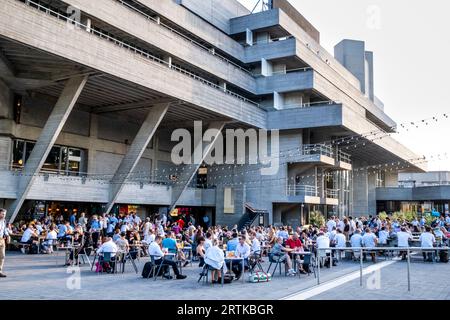 Leute, die an Tischen sitzen, trinken vor dem National Theatre, London, UK. Stockfoto