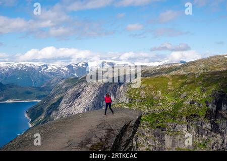 Eine Frau posiert auf Trolltunga (Trolls Zunge) mit Blick auf den Ringedalsvatnet Lake, in der Nähe von Tyssedal, Vestland, Norwegen. Stockfoto