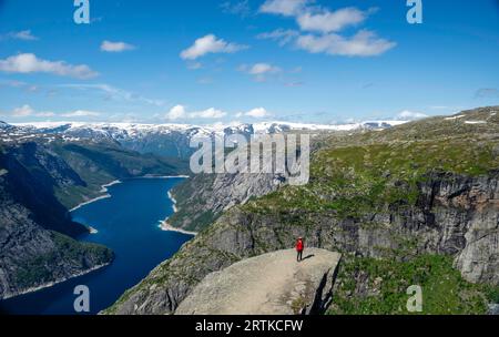 Eine Frau posiert auf Trolltunga (Trolls Zunge) mit Blick auf den Ringedalsvatnet Lake, in der Nähe von Tyssedal, Vestland, Norwegen. Stockfoto