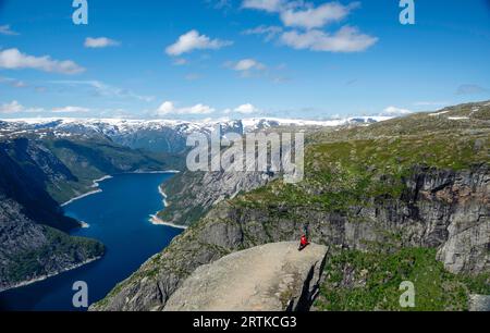 Eine Frau posiert auf Trolltunga (Trolls Zunge) mit Blick auf den Ringedalsvatnet Lake, in der Nähe von Tyssedal, Vestland, Norwegen. Stockfoto