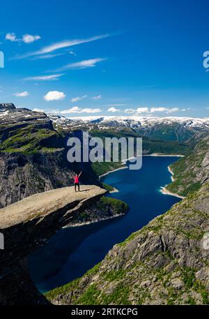 Eine Frau posiert auf Trolltunga (Trolls Zunge) mit Blick auf den Ringedalsvatnet Lake, in der Nähe von Tyssedal, Vestland, Norwegen. Stockfoto