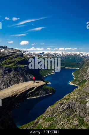 Eine Frau posiert auf Trolltunga (Trolls Zunge) mit Blick auf den Ringedalsvatnet Lake, in der Nähe von Tyssedal, Vestland, Norwegen. Stockfoto