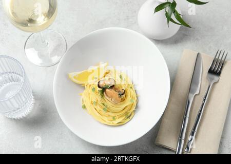 Leckere Capellini mit Miesmuscheln und Zitrone serviert auf hellgrauem Tisch, Blick über den Tisch. Exquisite Präsentation von Nudelgerichten Stockfoto