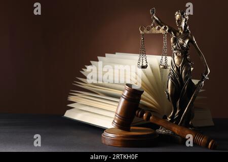 Statue von Lady Justice in der Nähe des Nabels und offenes Buch auf grauem Tisch, Platz für Text. Symbol der gerechten Behandlung nach dem Gesetz Stockfoto