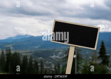 Leeres Tafeletikett mit Kopierfeld auf dem Hintergrund der schneebedeckten Berge, grüne Wälder im Nationalpark Zakopane Polen. Berglandschaft. Reisen Sie im Freien Grünes Tourismuskonzept Naturecore. Wandern und Wohlbefinden Stockfoto