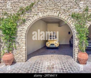 Ein gelber Deux Chevaux parkte in der Garage eines Steinhauses in der Provence, Frankreich Stockfoto