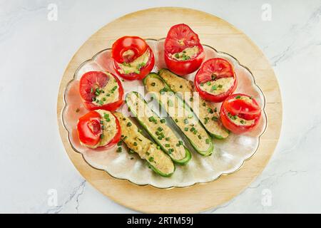 Gefüllte Tomaten und Gurken mit grünen Zwiebeln auf dem Teller Stockfoto