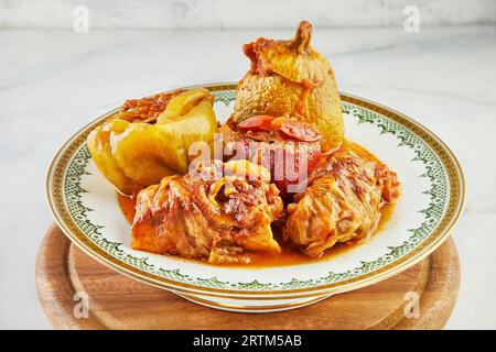 Gefüllte Zucchini, Paprika und Kohlrollen auf Teller mit einem Ornament auf Holzständer Stockfoto