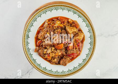 Rindereintopf mit Knoblauch und Karotten in Rotwein auf Teller mit Ornament Stockfoto