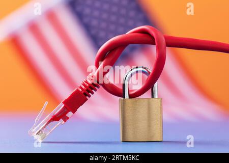 Geschlossenes Vorhängeschloss auf einem geknüpften Netzwerkkabel auf dem Hintergrund der amerikanischen Flagge, Internet-Technologie-Sicherheitskonzept in den USA Stockfoto