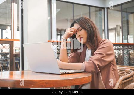 Porträt einer verschlafenen attraktiven asiatischen Freiberuflerin, die sich nach Überlastung gestern Abend müde fühlt Stockfoto