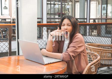 Porträt einer verschlafenen attraktiven asiatischen Freiberuflerin, die sich nach Überlastung gestern Abend müde fühlt Stockfoto