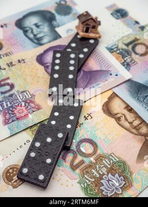 domino-Effekt und Haus auf chinesischer Yuan-Währung Hintergrund Konzeptfoto Stockfoto