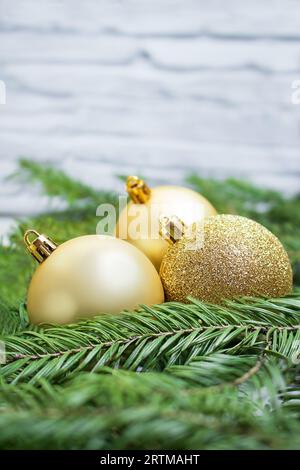 Goldene Kugeln im Tannennest gegen weiße Wand. Neujahr, Weihnachten, Urlaub, Geschäft. Leerzeichen kopieren Stockfoto