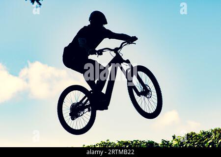 Silhouette eines Bikers, der mit einem bmx-Bike einen extrem schmutzigen Sprung gegen den Himmel macht Stockfoto