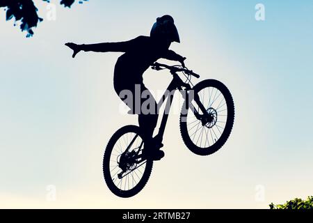 Silhouette eines Bikers, der mit einem bmx-Bike einen extrem schmutzigen Sprung gegen den Himmel macht Stockfoto